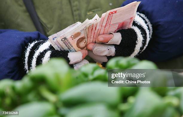 Vendor counts notes at the Xinfadi Vegetable Auction Market on February 25, 2007 in Beijing, China. Xinfadi is the largest of the 4000 vegetable...