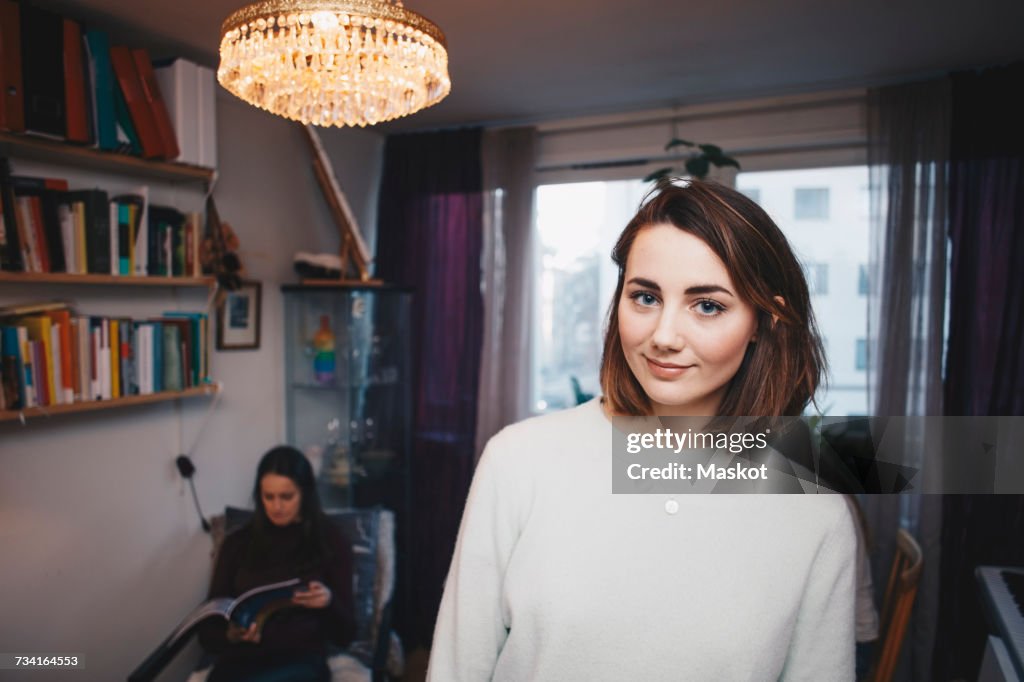 Portrait of young woman with female friend sittings in college dorm room