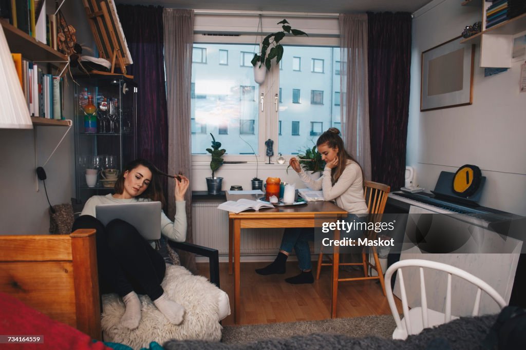 Young female roommates studying together in college dorm room