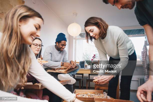 happy young friends eating pizza in college dorm room - college dorm party stock-fotos und bilder