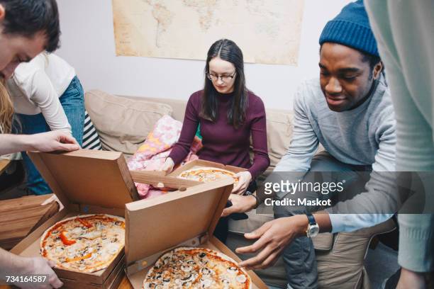 high angle view of young friends opening pizza boxes in dorm room - college dorm party stock pictures, royalty-free photos & images
