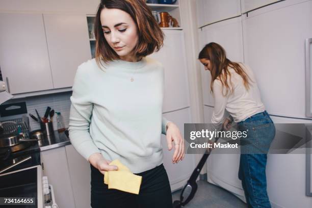 female roommates cleaning kitchen in college dorm - vacuum cleaner woman stock pictures, royalty-free photos & images