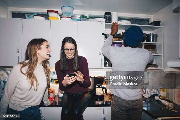 female friends enjoying by man in kitchen at college dorm - parceiro de apartamento - fotografias e filmes do acervo