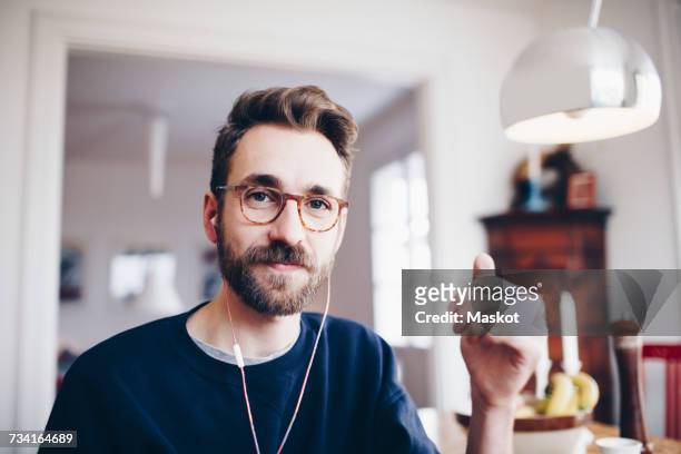 portrait of happy man listening to music in headphones at home - man happy stockfoto's en -beelden