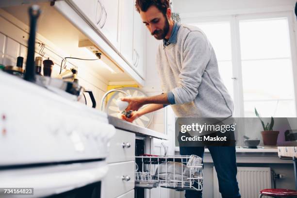 man cleaning utensils in kitchen at home - dirty dishes stockfoto's en -beelden