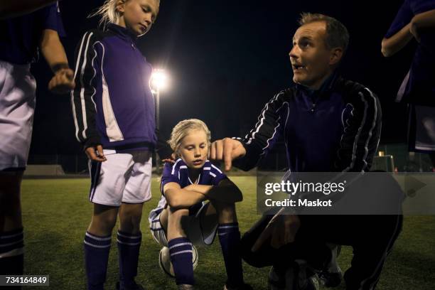 coach explaining strategy to girls on soccer field at night - football training stockfoto's en -beelden