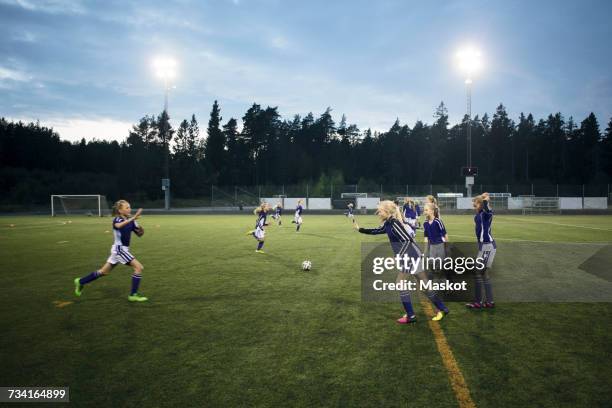 girls running on soccer field against sky - jugendfußball stock-fotos und bilder