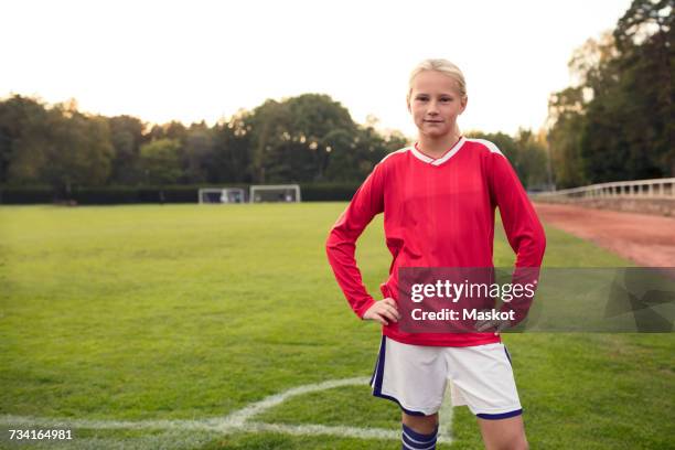 portrait of confident girl standing on soccer field - tenue de football photos et images de collection