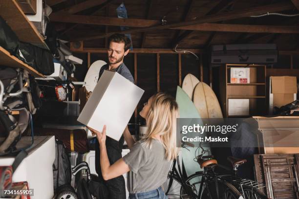 mid adult couple arranging box in storage room - arrangement stock pictures, royalty-free photos & images