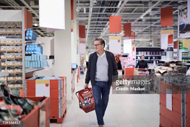 mature man walking with basket in supermarket - supermarket interior stock pictures, royalty-free photos & images