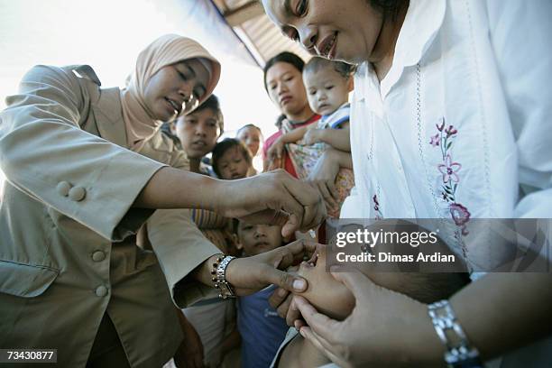 An Indonesian health worker vaccinates an Indonesian child against polio after measles immunisation February 27, 2007 in Jakarta, Indonesia....