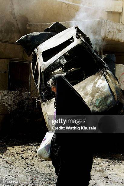 An Iraqi woman walks past the site of a car bomb explosion on February 27, 2007 in the Karrada Shiite neighborhood in Baghdad, Iraq. At least two...