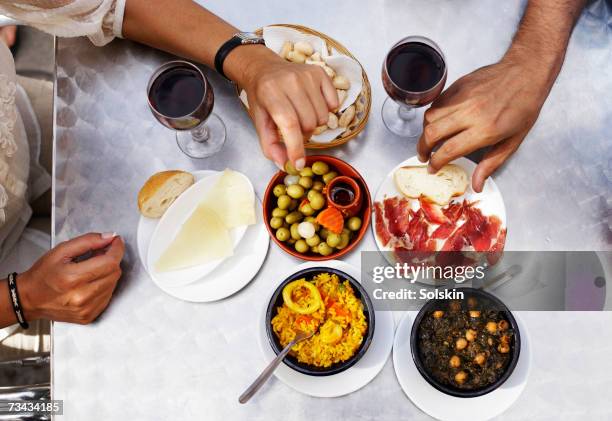 people eating tapas at outdoor restaurant, close-up of hands, overhead view - tapas stock-fotos und bilder