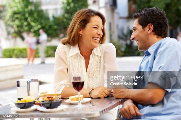 couple laughing over meal at outdoor restaurant - tapas spain stock pictures, royalty-free photos & images