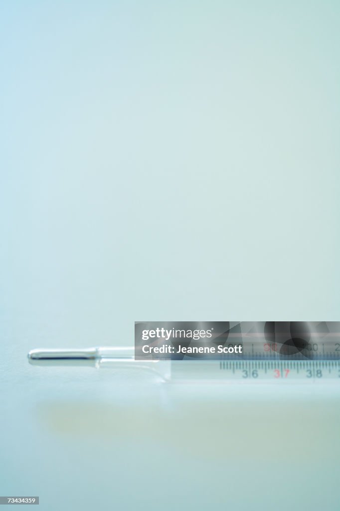 Mercury thermometer on blue background, close-up