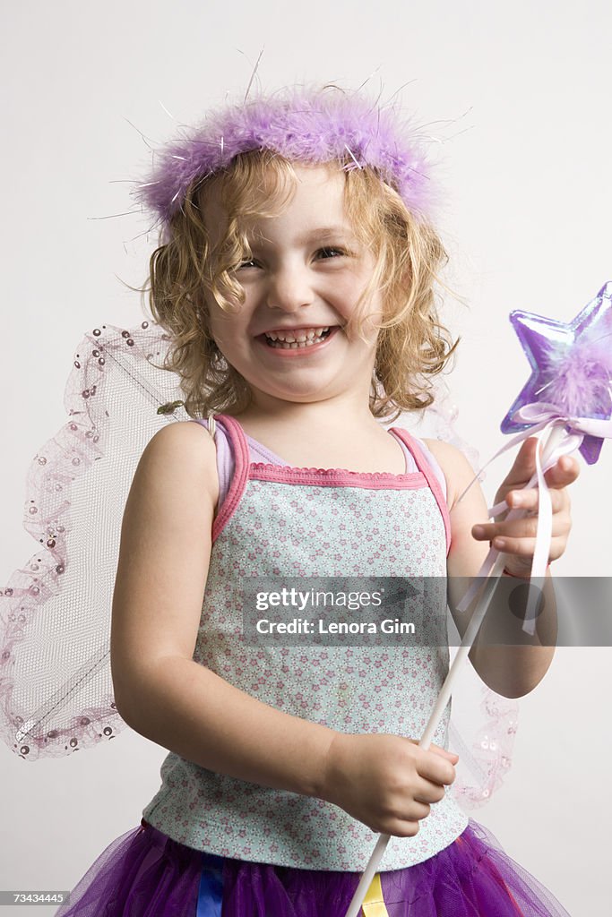 Girl (2-4) dressing up in fairy costume, smiling, portrait