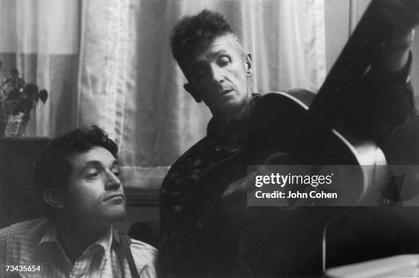American folk musician Ramblin' Jack Elliott , born Elliott Charles Adnopoz, watches his mentor Woody Guthrie as he demonstrates playing the guitar,...