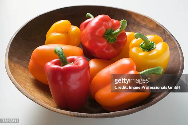 yellow, orange and red peppers in wooden bowl - orange bell pepper stock pictures, royalty-free photos & images
