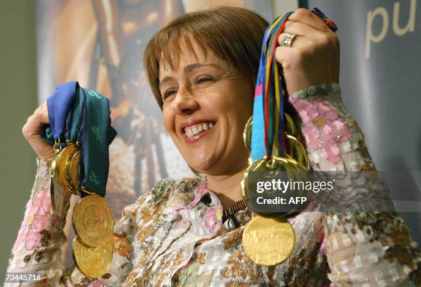 London, UNITED KINGDOM: Britain's paralympian Dame Tanni Grey Thompson holds up her gold medals at a press conference in London as she announces her...