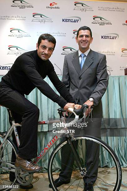 Abu Dhabi, UNITED ARAB EMIRATES: Spanish Melchor Mauri and Abraham Olano pose with a bicycle during the 'Speech for the Abu Dhabi Race of Champions'...