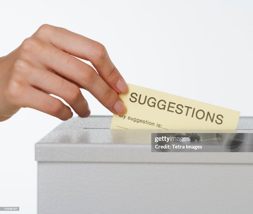 Close up of woman's hand putting card in suggestion box