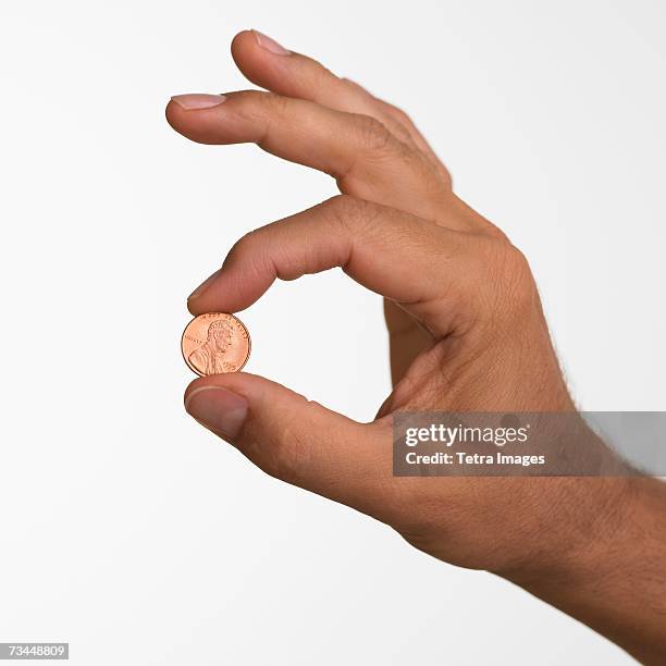 close up studio shot of man holding penny - one cent coin stock pictures, royalty-free photos & images