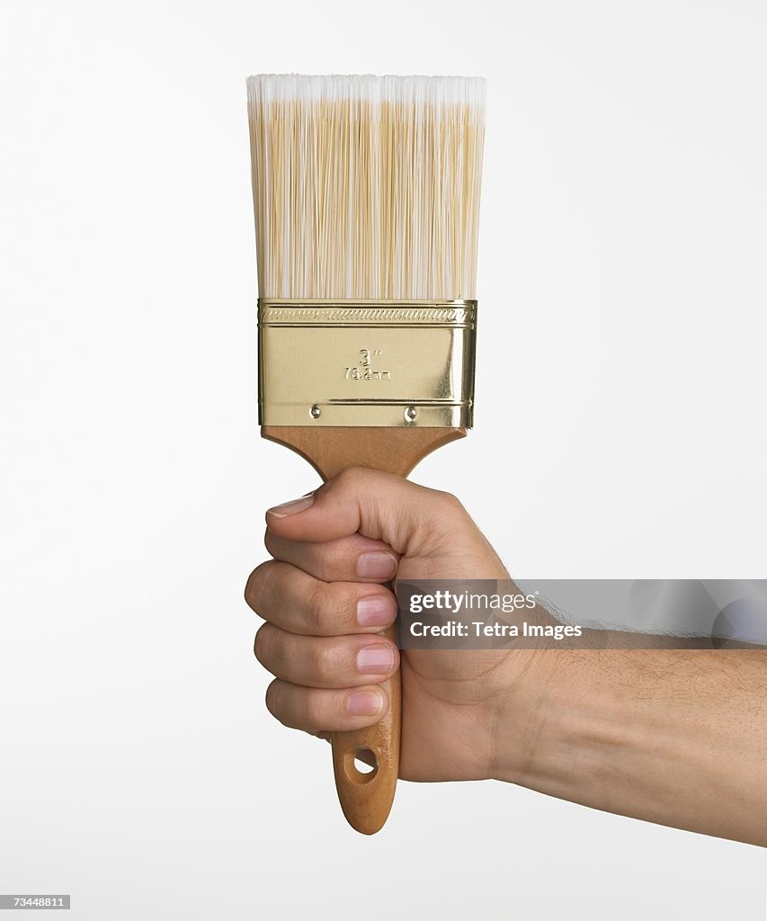 Close up studio shot of man holding paintbrush
