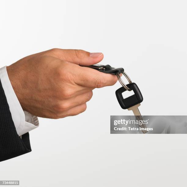 close up studio shot of man holding car keys - key drop stock pictures, royalty-free photos & images