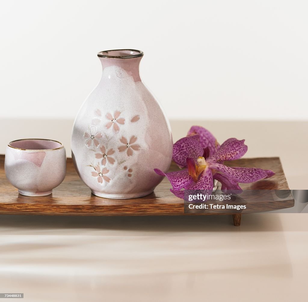 Close up of jug and cup with flower on tray