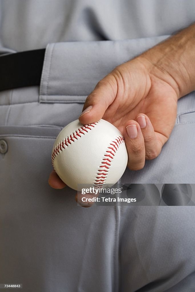 Close up baseball pitcher holding baseball behind back