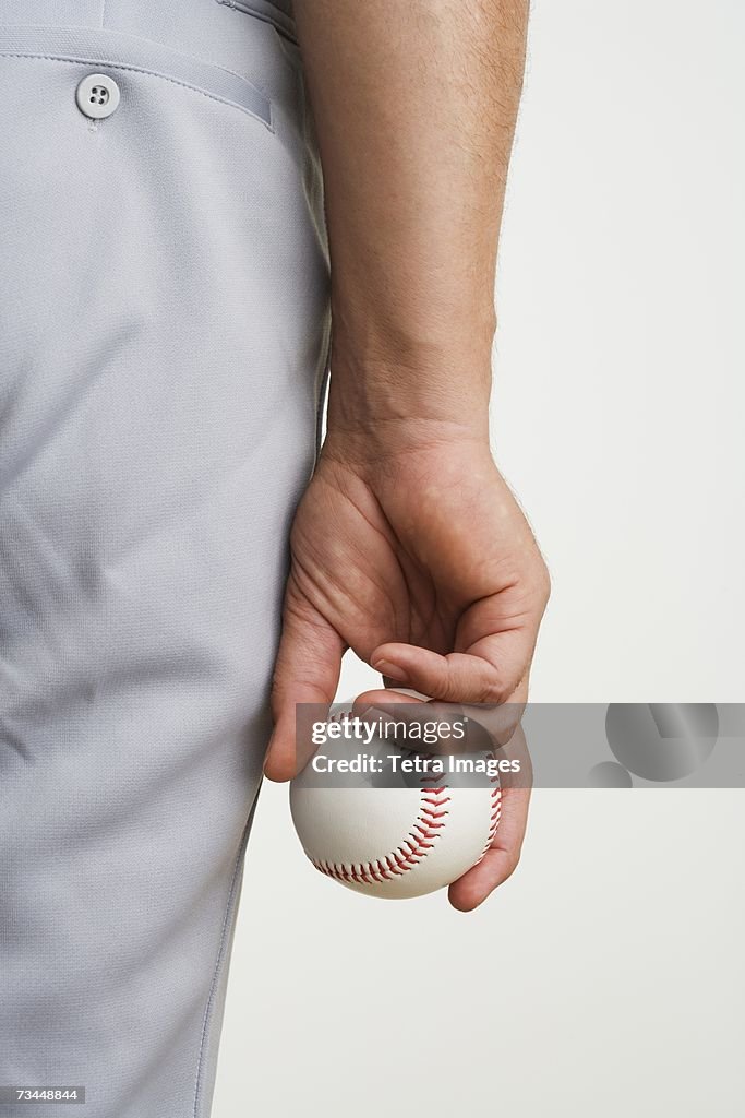 Close up of man holding baseball at side