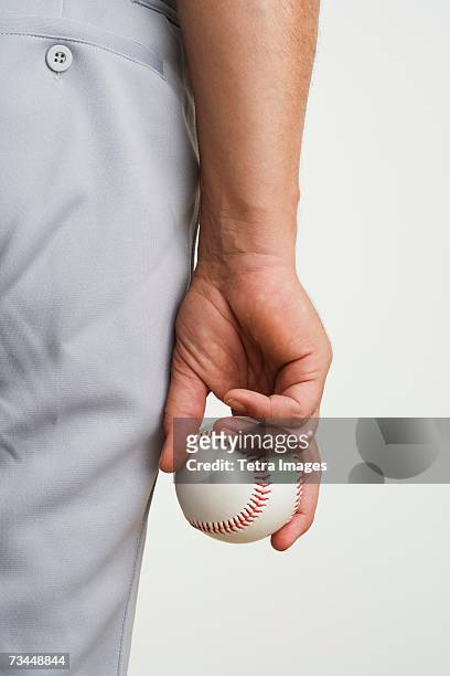 close up of man holding baseball at side - baseball pitcher close up stock pictures, royalty-free photos & images