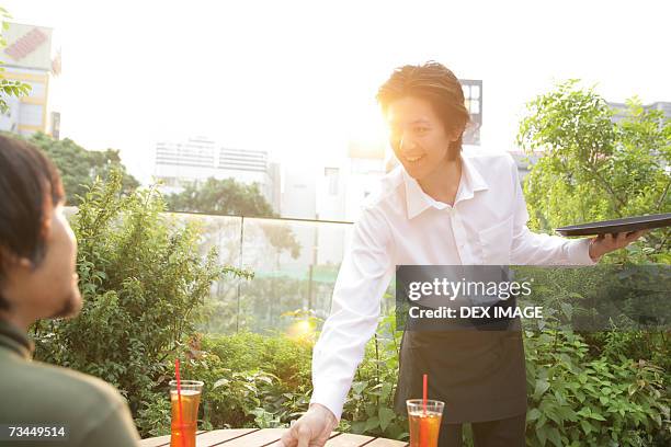 waiter serving drinks to a man and smiling - bendy straw stock pictures, royalty-free photos & images