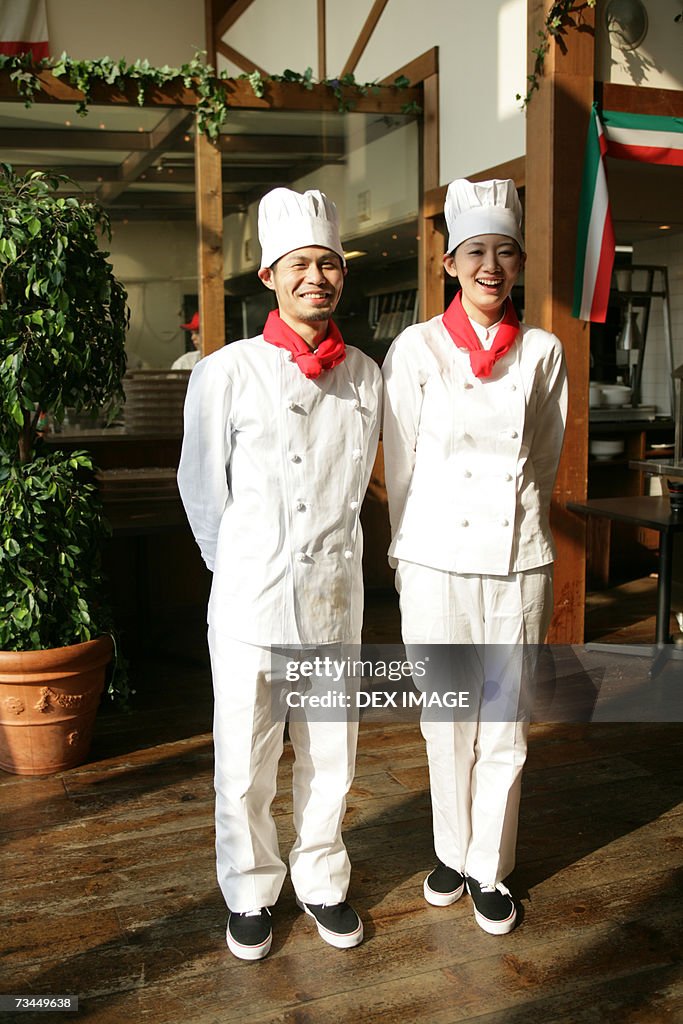 Portrait of two chefs standing in front of a restaurant