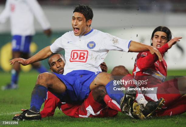 Malik Fathi of Hertha sits on Cacao of Stuttgart while his team mate Sami Khedira watches during the DFB German Cup quarter final match between VfB...