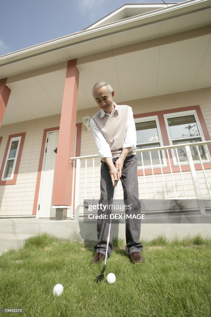 Low angle view of a senior man playing golf in front of a house