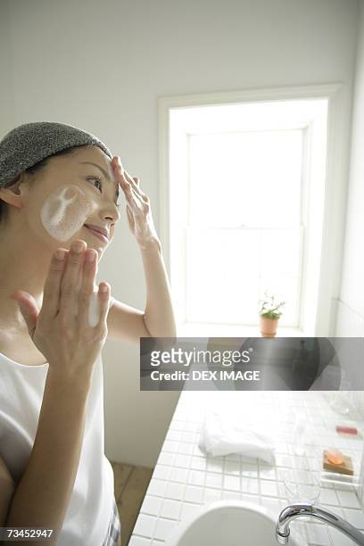 side profile of a young woman applying soap on her face - tap forehead stock pictures, royalty-free photos & images