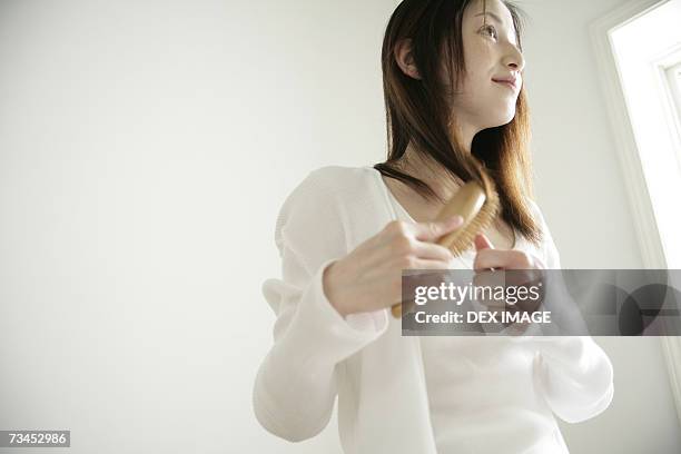 close-up of a young woman combing her hair - combing ストックフォトと画像