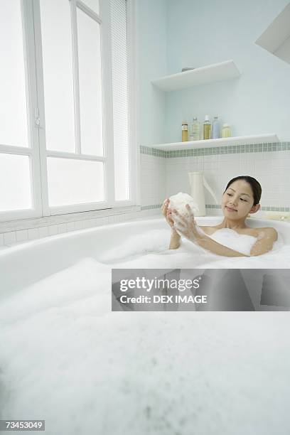 young woman taking a bubble bath - bubble bath bottle stock pictures, royalty-free photos & images