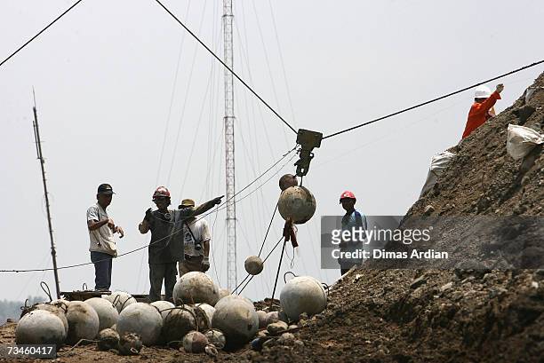 Indonesian workers drop chained concrete balls to help stem mudflow, March 1, 2007 in Sidoarjo, East Java, Indonesia. Over the next few weeks,...
