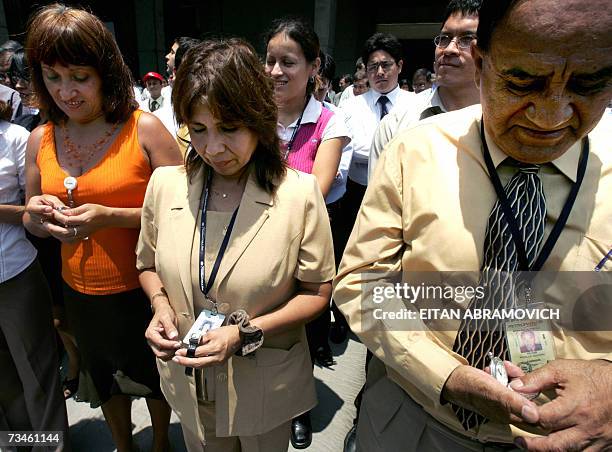 Trabajadores de una empresa estatal en Lima ajustan sus relojes a la hora durante el inicio de una campana del estado por la puntualidad el 01 de...