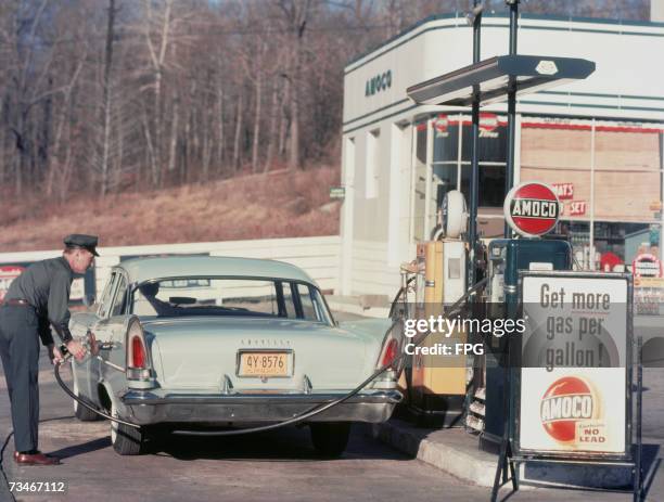 Petrol pump attendant filling up a Chrysler car at an Amoco station, 1958.