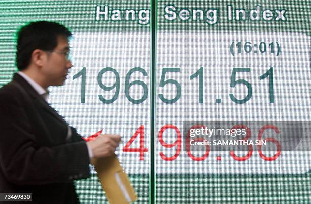 Man walks past a board displaying the Hang Seng Index outside a bank in Hong Kong, 28 February 2007. Hong Kong share prices closed sharply lower,...