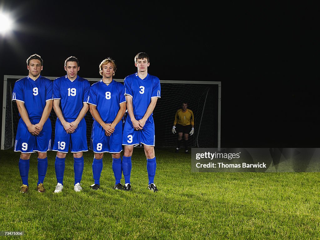 Male soccer players in defensive wall awaiting free kick