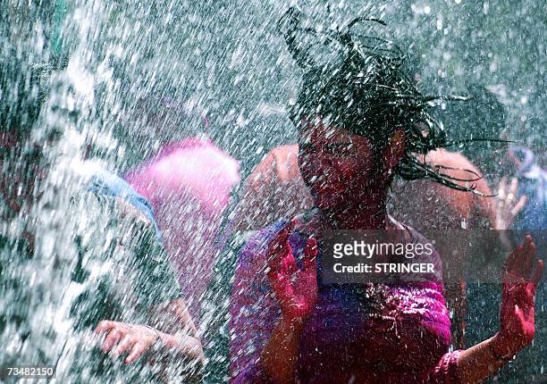 An Indian girls dances in artificial rain as she celebrates the festival of Holi, in Hyderabad on 03 March 2007. Holi, the festival of colours, is...