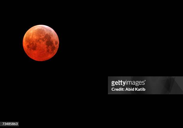 The moon glows red in the shadow of the earth during the first total lunar eclipse in three years on March 3, 2007 over Gaza City, Gaza Strip. The...