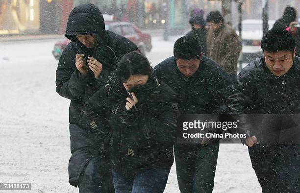 Passers-by walk in wind and snow at a street on March 4, 2007 in Changchun of Jilin Province, China. A moderate rain and snow began to hit most parts...