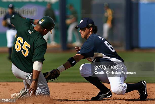 Infielder Luis Cruz of the San Diego Padres tags out Javier Herrera of the Oakland Athletics attempting to steal second base during the MLB spring...
