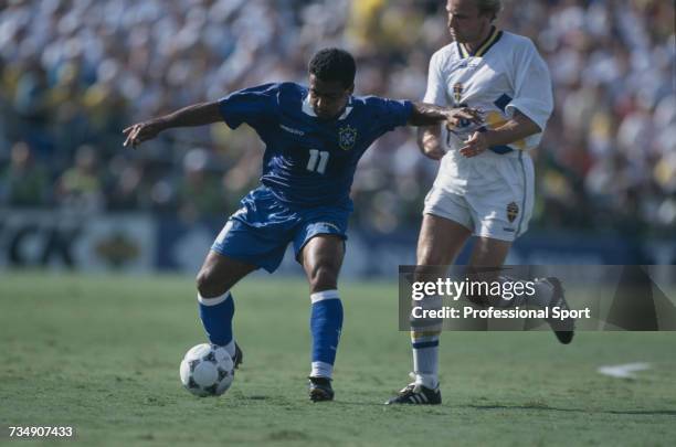 Brazilian footballer Romario pictured in action with the ball as Swedish footballer Hakan Mild attempts a tackle during play in the 1994 FIFA World...