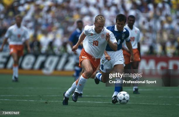 Dutch footballer Dennis Bergkamp makes a run with the ball as Brazil captain Dunga follows closely during play in the 1994 FIFA World Cup...